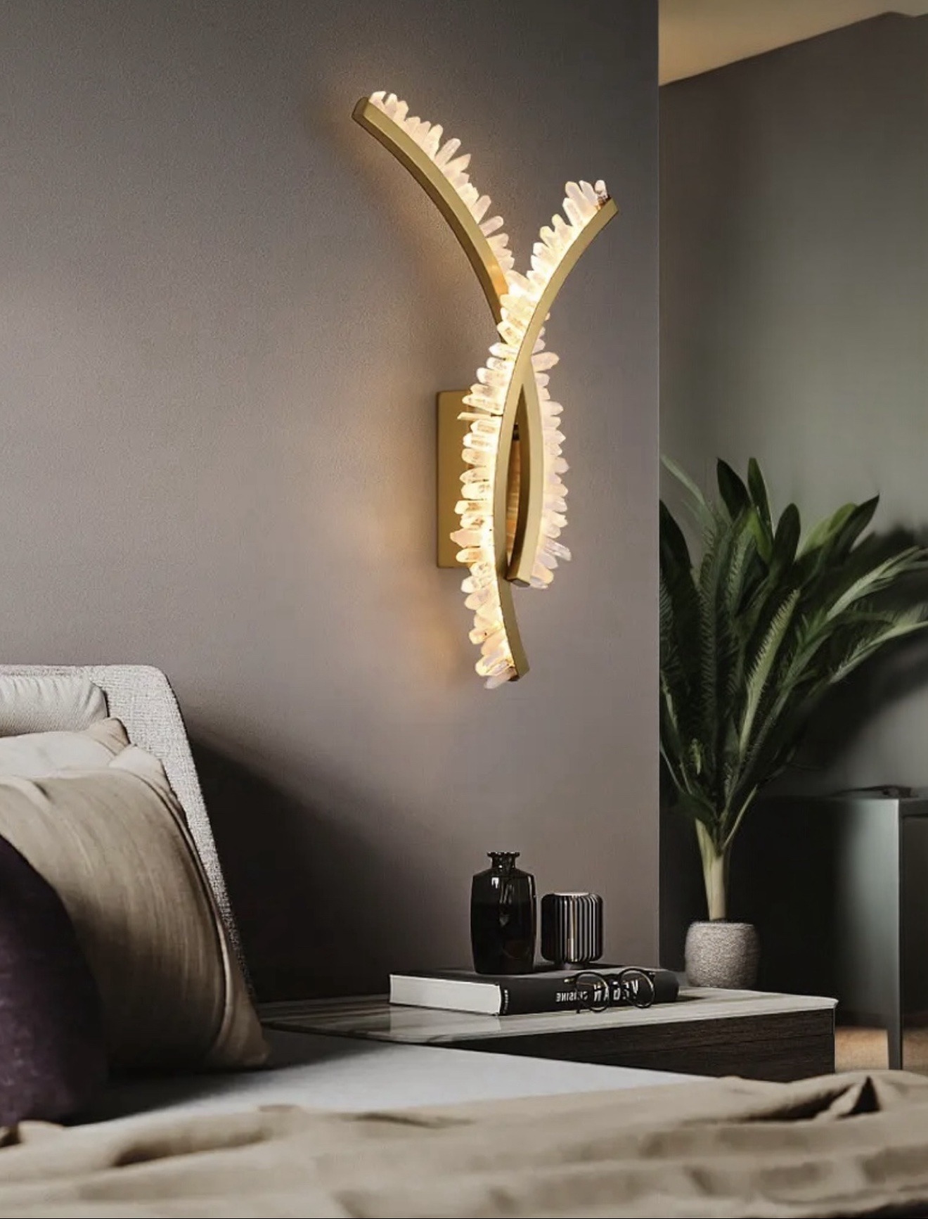 Curved brass wall sconce edged with clear quartz points, glowing in a bedroom