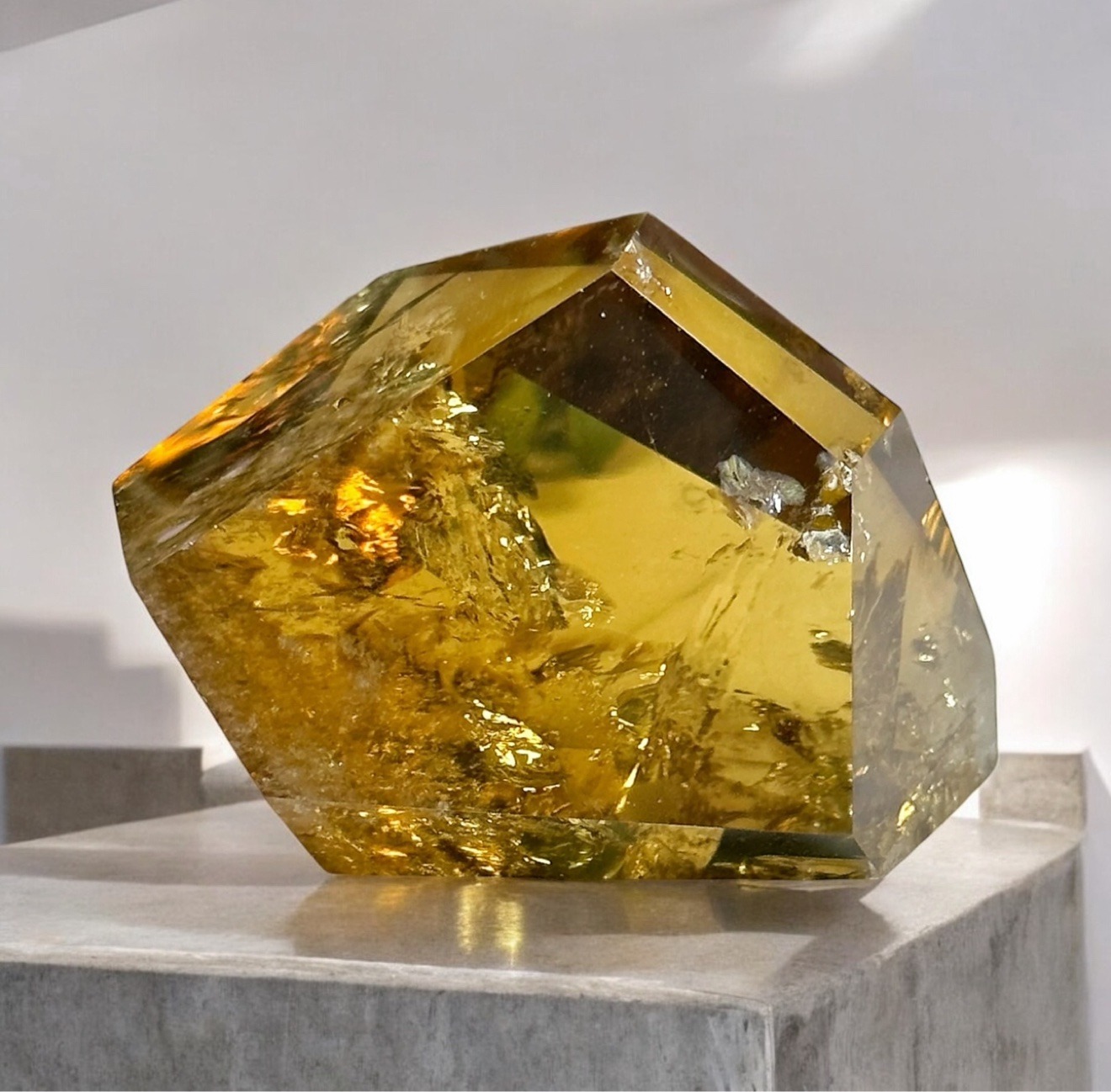 Large faceted golden citrine glowing on a marble pedestal in a bright gallery
